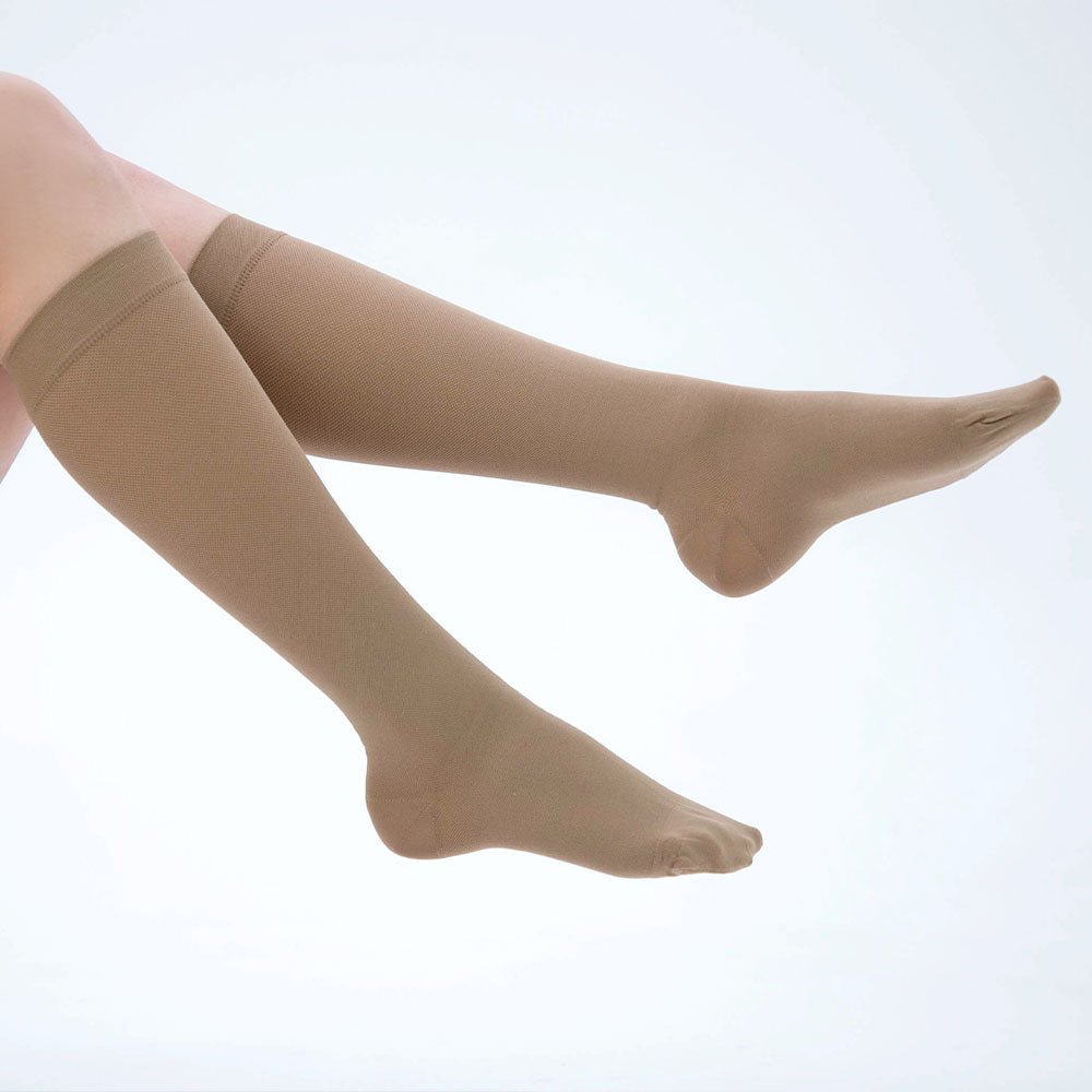 Knee-high compression socks in beige, providing 15-20 mmHg pressure, ideal for reducing leg fatigue and swelling.